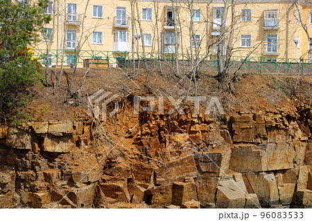 A multi-storey building standing on a cliff of a rocky shore. A multi-storey building standing on a cliff of a rocky shore. 96083533