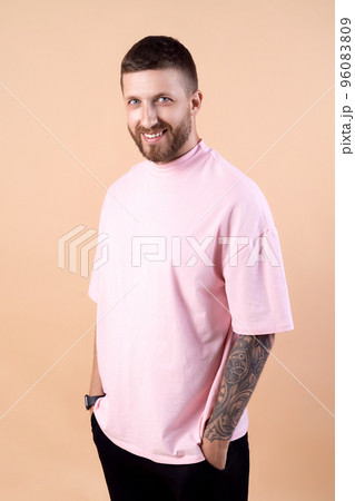 bearded hipster man with stylish haircut and tattoo in fashionable casual clothes pink t-shirt bearded hipster man with stylish haircut and tattoo in fashionable casual clothes pink t-shirt 96083809