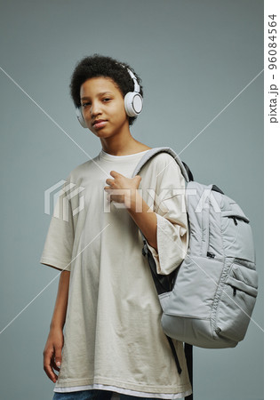 Cute schoolgirl in long white t-shirt and headphnes holding backpack Cute schoolgirl in long white t-shirt and headphnes holding backpack 96084564