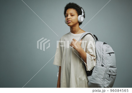 Cute AFrican American schoolgirl with backpack listening to music Cute AFrican American schoolgirl with backpack listening to music 96084565