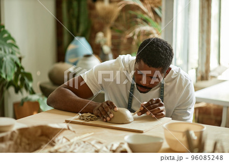 Male artist shaping handmade ceramic bowl in pottery studio 96085248