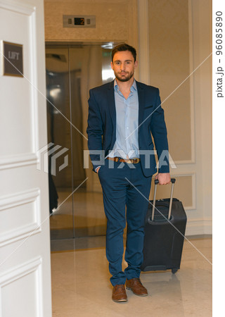 Happy young man with travel bag walking inside hotel 96085890