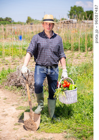 Happy farmer with basket of vegetables in the garden 96087487