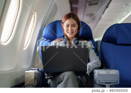 portrait of A successful asian business woman or female entrepreneur in formal suit in a plane sits in a business class seat and uses a computer laptop during flight. portrait of A successful asian business woman or female entrepreneur in formal suit in a plane sits in a business class seat and uses a computer laptop during flight. 96090000