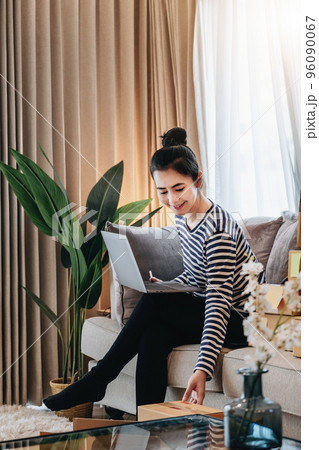 Online merchandising business idea, a beautiful girl is using a computer to check orders to deliver parcels to customers according to orders received from customers 96090067