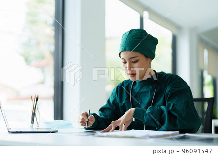 Portrait of an Asian doctor looking at patient X-ray film to analyze the abnormality of the client's body. Portrait of an Asian doctor looking at patient X-ray film to analyze the abnormality of the client's body. 96091547