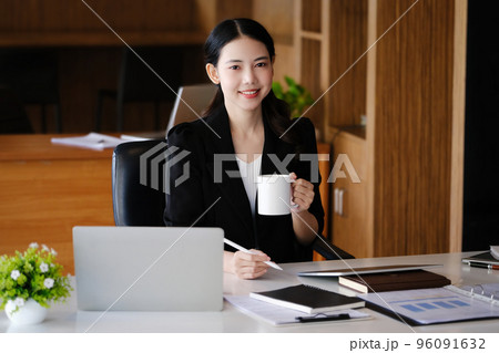 Company employees are sitting at work using computers, tablets and documents in their work 96091632