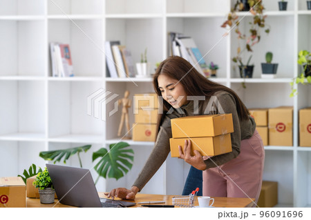 Work from home. happy women selling products online Start a small business owner by using laptop computer to calculate prices and prepare for postage Work from home. happy women selling products online Start a small business owner by using laptop computer to calculate prices and prepare for postage 96091696