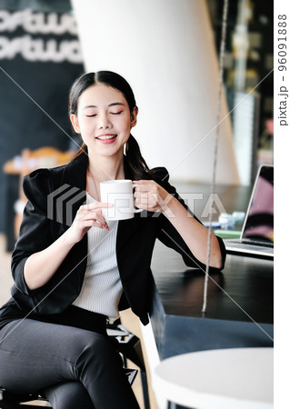 A female marketing manager is resting with a cup of coffee before returning to work to reduce drowsiness A female marketing manager is resting with a cup of coffee before returning to work to reduce drowsiness 96091888