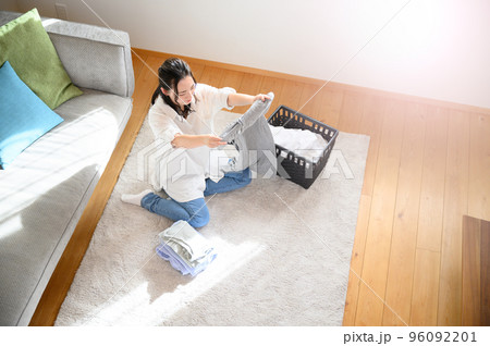 タオルなど洗濯物を畳む女性　笑顔　俯瞰の広角	 96092201