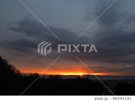 猪苗代湖の対岸に沈む夕日。厚い雲の地平線近くの切れ間から赤いスポットライトの様に太陽が輝き、綺麗だ。 96094191