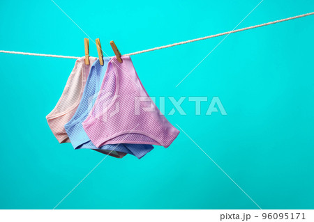 Female panties hanging on rope against blue studio background Female panties hanging on rope against blue studio background 96095171