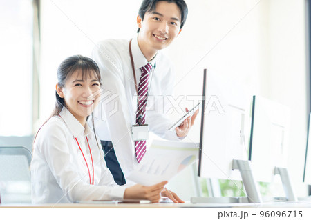 デスクで打ち合わせをする若い男女 デスクで打ち合わせをする若い男女 96096715