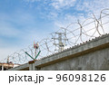 view of a high concrete fence with barbed wire at the top 96098126