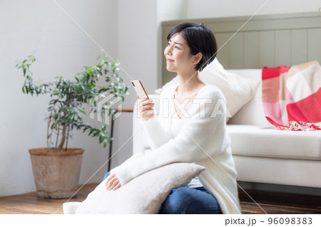 リビングの床に座りスマホを見ている女性 リビングの床に座りスマホを見ている女性 96098383
