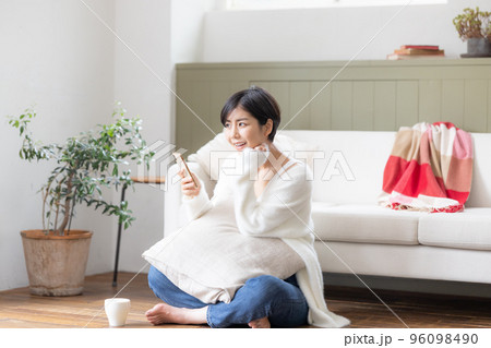 リビングの床に座りスマホを見ている女性 リビングの床に座りスマホを見ている女性 96098490