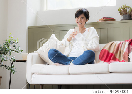 ソファーに座りスマホを見ている女性 96098801