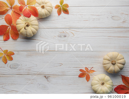 Autumn leaves and pumpkins over old wooden background 96100019