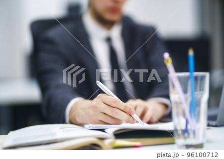 Pen in office worker hand. Close up of the hands of a businessman in a suit signing a document. Pen in office worker hand. Close up of the hands of a businessman in a suit signing a document. 96100712