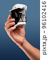 Male hand holds, raised black crumpled paper cup of tea or coffee. 96102416
