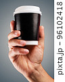 Male hand holds, raised black paper cup of tea or coffee. 96102418
