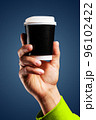 Male hand holds, raised black paper cup of tea or coffee. 96102422