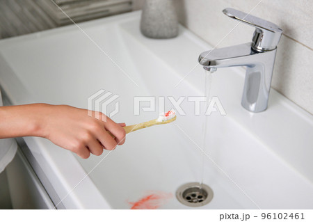 Blood on toothbrush on background of sink. Selective focus on the toothbrush. Blood on toothbrush on background of sink. Selective focus on the toothbrush. 96102461