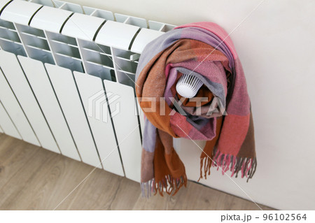 The radiator is wrapped in a multicolored warm scarf. 96102564