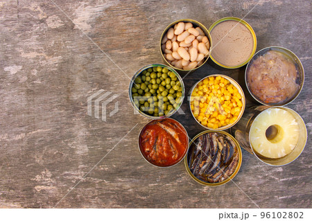 Different open canned food on old wooden background. Top view. Flat lay. 96102802