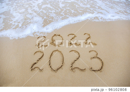 2023, 2022 years written on sandy beach sea. Wave washes away 2022. 2023, 2022 years written on sandy beach sea. Wave washes away 2022. 96102808