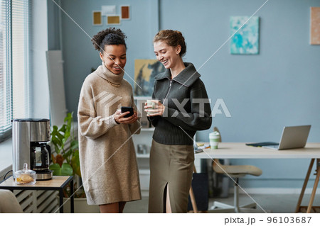 Colleagues using smartphone at coffee break 96103687