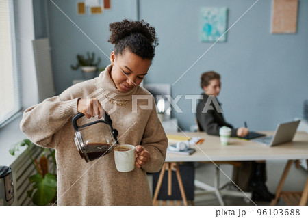 Businesswoman drinking coffee at office 96103688