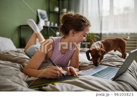 Girl drawing on graphic tablet in bed 96103823
