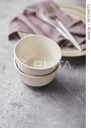 Two small empty salad bowls, plates and linen napkins on gray background Two small empty salad bowls, plates and linen napkins on gray background 96104075