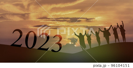 Happy new year 2023, Keep fighting together, Silhouette of 2023 letters on the mountain with business people raised arms in teamwork concept at sunrise.. 96104151