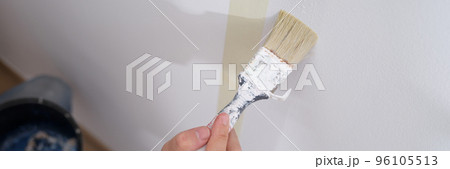 Manual worker holding brush and painting with white on wall of house 96105513