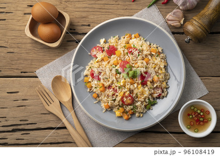Sausage Fried rice.Stir fried Thai rice with hot dog ,carrot and eggs in gray plate on wood table .Top view Sausage Fried rice.Stir fried Thai rice with hot dog ,carrot and eggs in gray plate on wood table .Top view 96108419