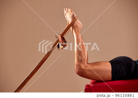 An athletic man does an exercise on a reformer in the gym. No face. Feet close-up on the reformer. Pilates. The concept of a healthy. High quality photo 96110861