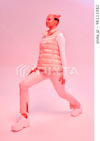 Woman in futuristic costume. Female in modern smart glasses interacting with network while having virtual reality experience. Augmented reality game, future technology, AI concept. VR. Neon pink light 96111082