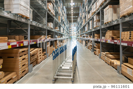 A row of trolleys for customers in a large warehouse in the aisle between shelves and racks A row of trolleys for customers in a large warehouse in the aisle between shelves and racks 96111601