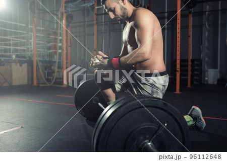 Athletic man works out at the gym with a barbell Athletic man works out at the gym with a barbell 96112648