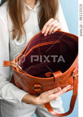 close-up photo of orange leather bag in a womans hands 96113310