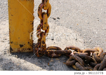 Old rusty yellow chain with large links close-up on a rack on the dock. 96113778