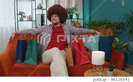 Happy adult man shopaholic consumer came back home after online shopping sale with bags at home 96116541