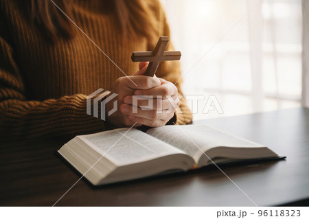 Woman sitting and studying the scriptures.The  wooden cross in the hands. Christian education concepts The Holy Scriptures open and pray 96118323