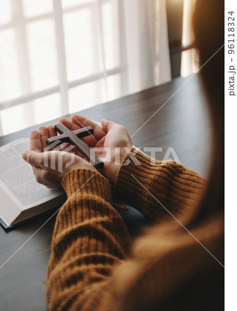 Woman sitting and studying the scriptures.The wooden cross in the hands. Christian education concepts The Holy Scriptures open and pray Woman sitting and studying the scriptures.The wooden cross in the hands. Christian education concepts The Holy Scriptures open and pray 96118324