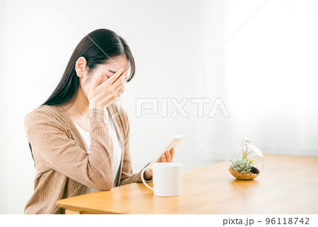 失恋でスマホを見てショックを受ける女性 96118742