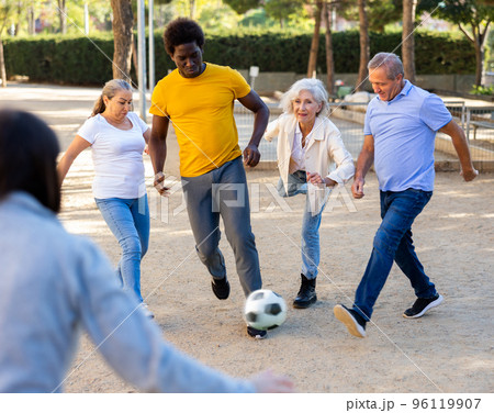 Happy mature people playing football in park Happy mature people playing football in park 96119907
