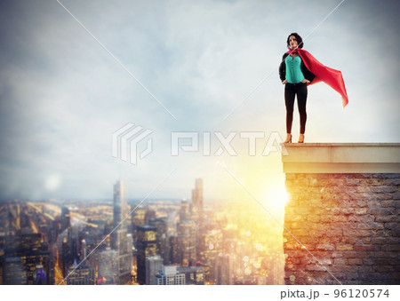 Successful businesswoman acts like a super hero above the roof of a building. Concept of determination and success Successful businesswoman acts like a super hero above the roof of a building. Concept of determination and success 96120574
