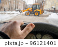 car driver hand on the steering wheel against the background of a tractor 96121401